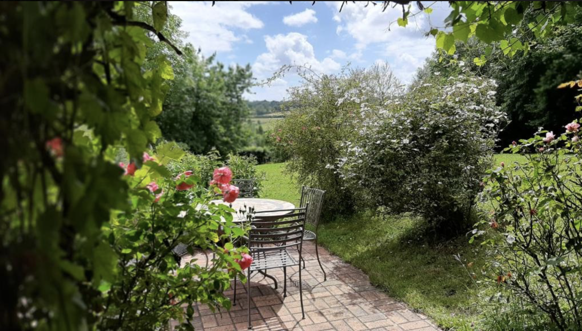 Jardin fleuri du cabinet d'hypnose de Sandrine Gauthier près de Livarot, à côté de Lisieux, avec vue sur la campagne normande